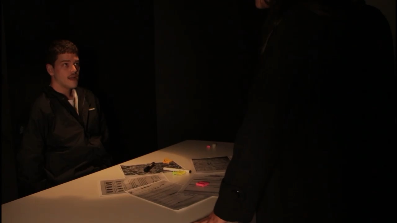 Cena do vídeo Bolovo Not-So Conspiracy: interrogatório numa mesa com papéis